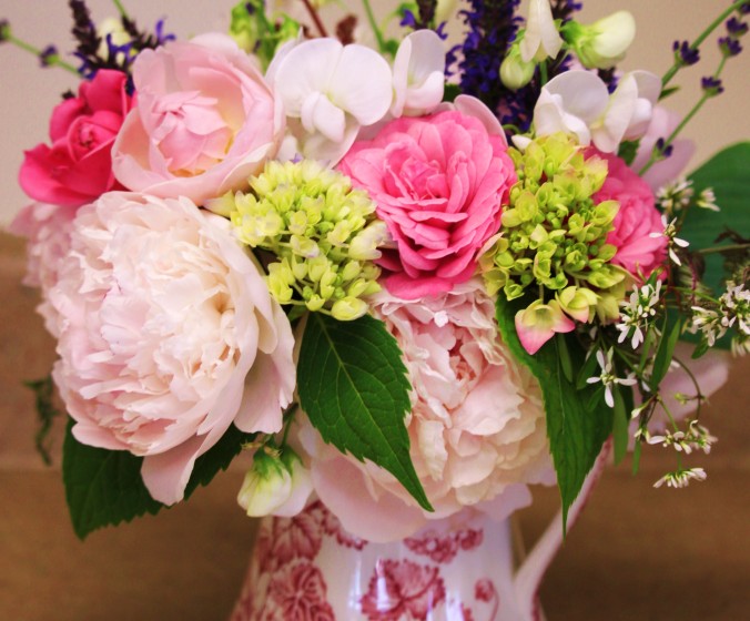 A traditional arrangement in a transferware pitcher:  the lime green unopened hydrangea, dark green hydrangea leaves and rich purple lavender ground the soft pinks of roses and peonies, while the pitcher gives the arrangement a classic feeling.